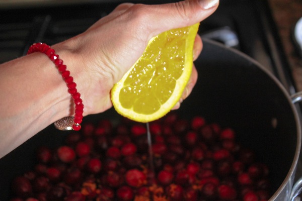 Squeezing an orange over cranberries